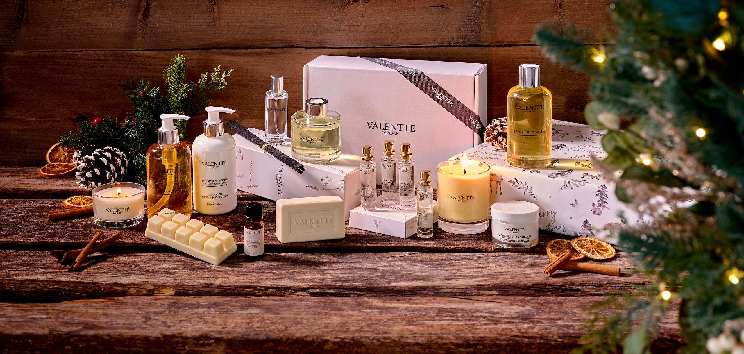 Valentte Christmas gifts arranged on a rustic wooden table beside a Christmas tree